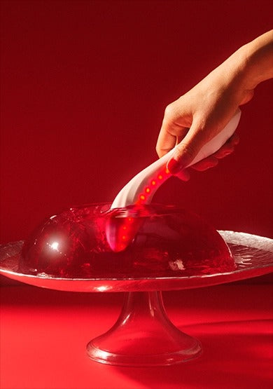 Hand holding the waterproof LELO MONA Spectra with red LEDs